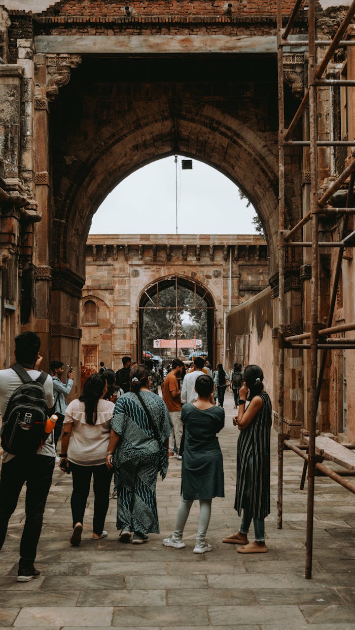 Group of tourists walking under historic arches in Ahmedabad, India, exploring local architecture.
